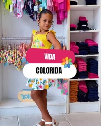 Criança usando vestido amarelo estampado dentro da loja Kids